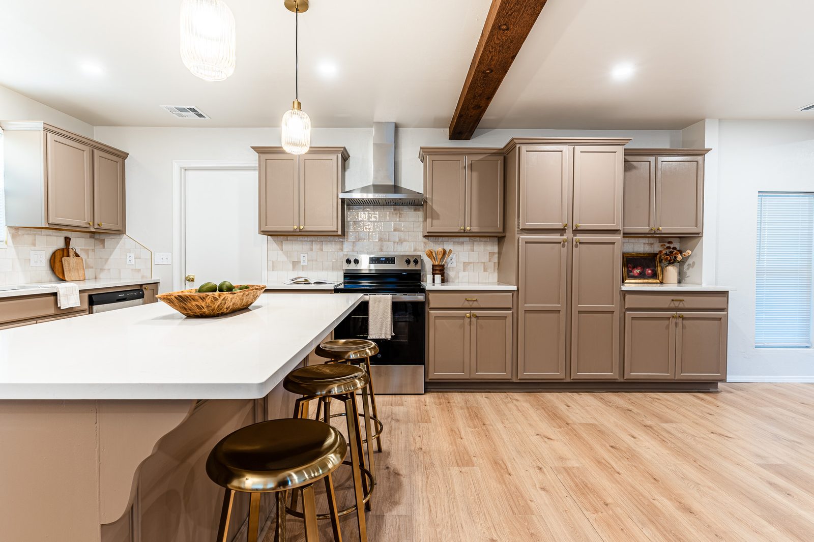 Remodeled kitchen with quartz island, gold bar stools and taupe cabinets, listing photo in Edmond, OK