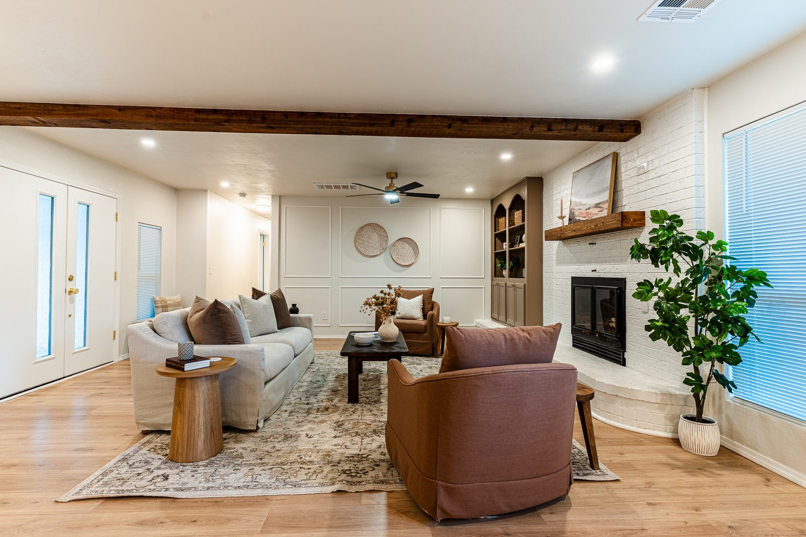 Bright staged living room with wood beam, white brick fireplace and built-in shelves, listing photo in Edmond, OK