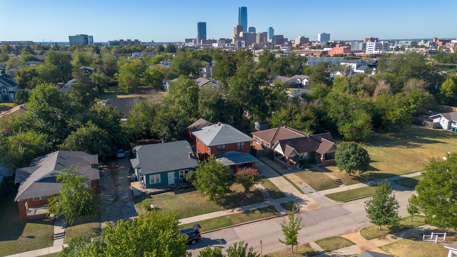 Aerial view of a brick home and neighborhood with the downtown skyline behind, listing photo in Oklahoma City, OK